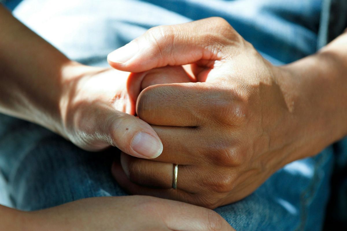 A younger hand gently holding an elderly person's hand